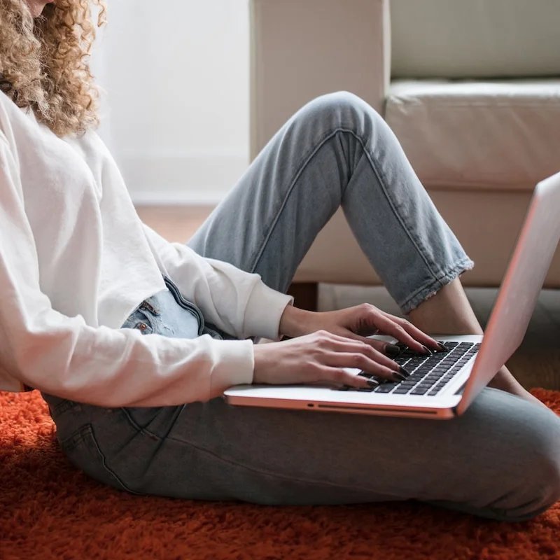 Woman sitting on the floor and typing on a laptop